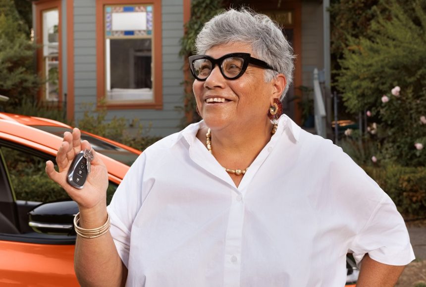 A woman with gray hair holding her car keys and smiling for a photo.
