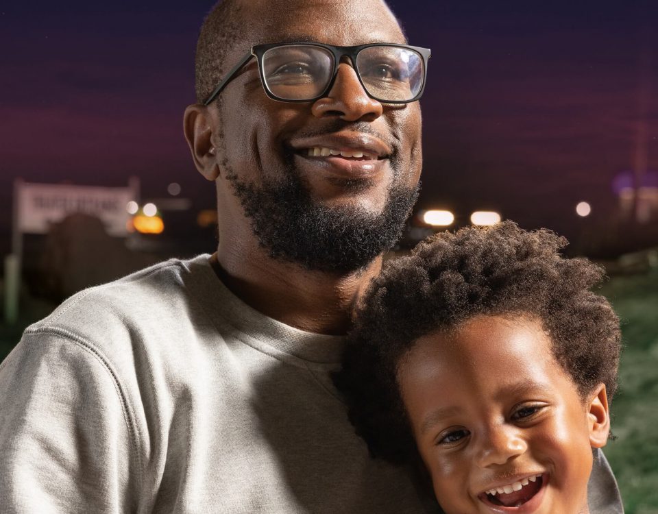 Father and a toddler smiling into the camera.